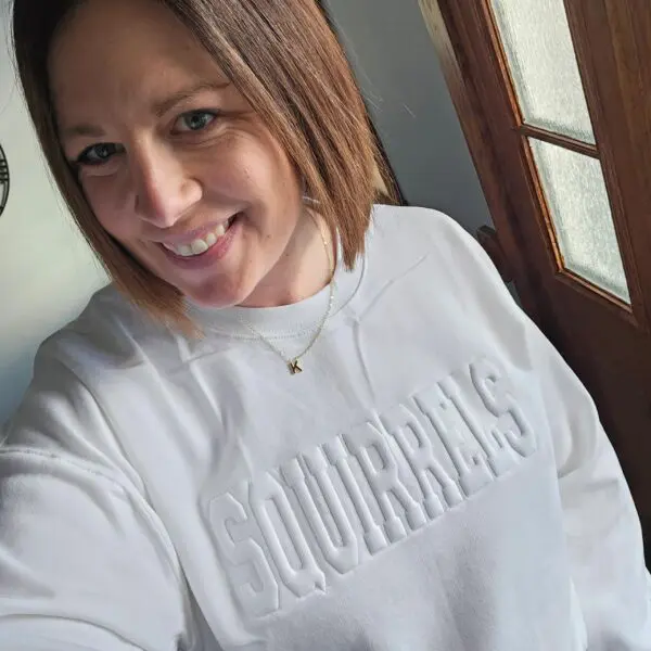 A woman in white sweater smiling for the camera.