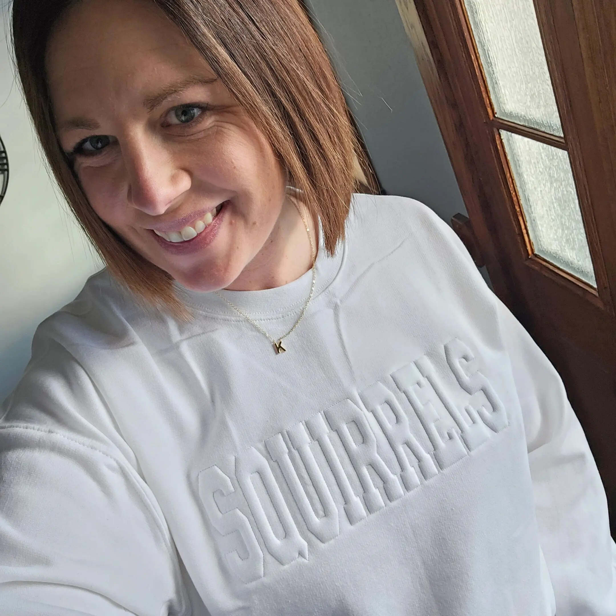 A woman in white sweater smiling for the camera.