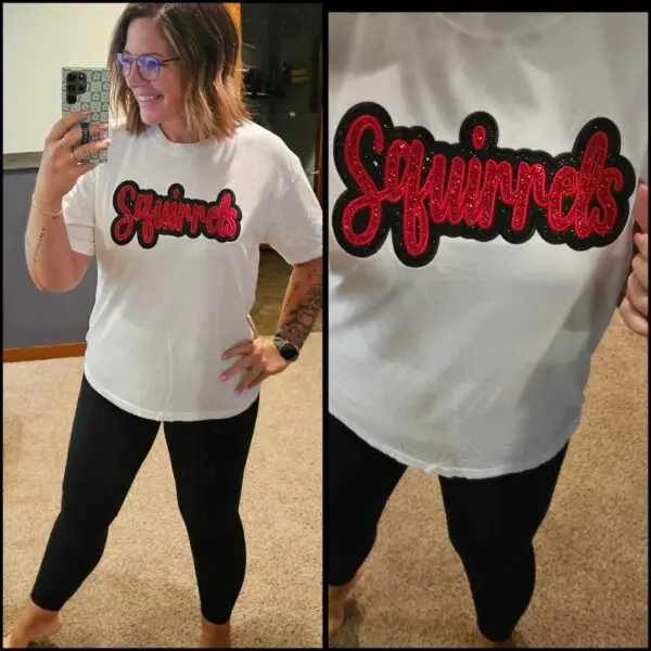 A woman in black pants and white shirt with red lettering.