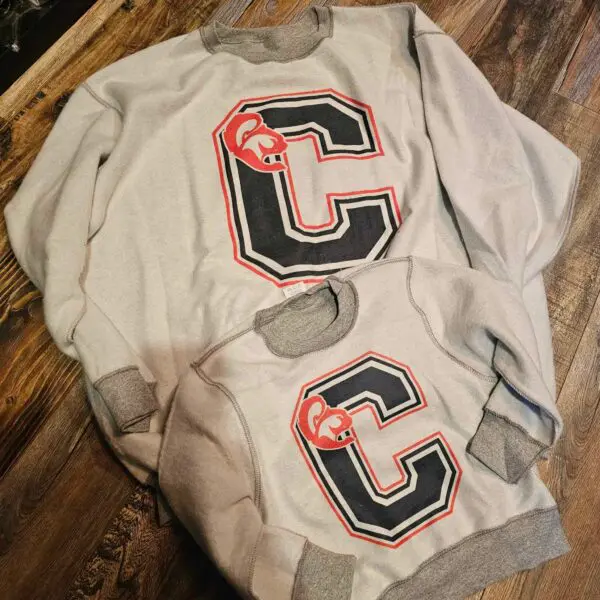 Two sweatshirt jackets sitting on top of a wooden table.