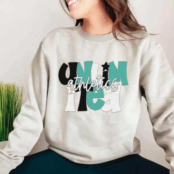 A woman sitting on the ground wearing a sweatshirt.