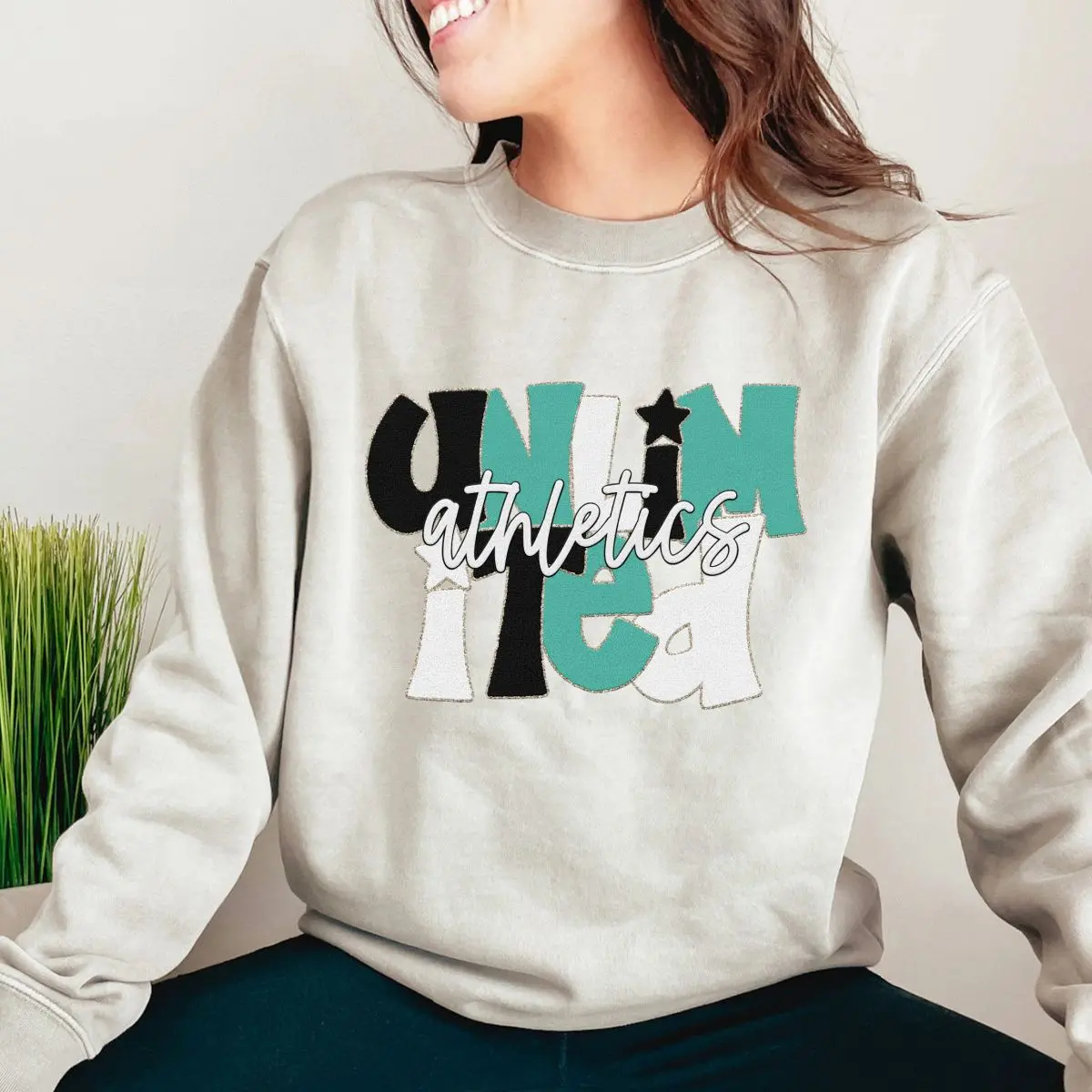 A woman sitting on the ground wearing a sweatshirt.