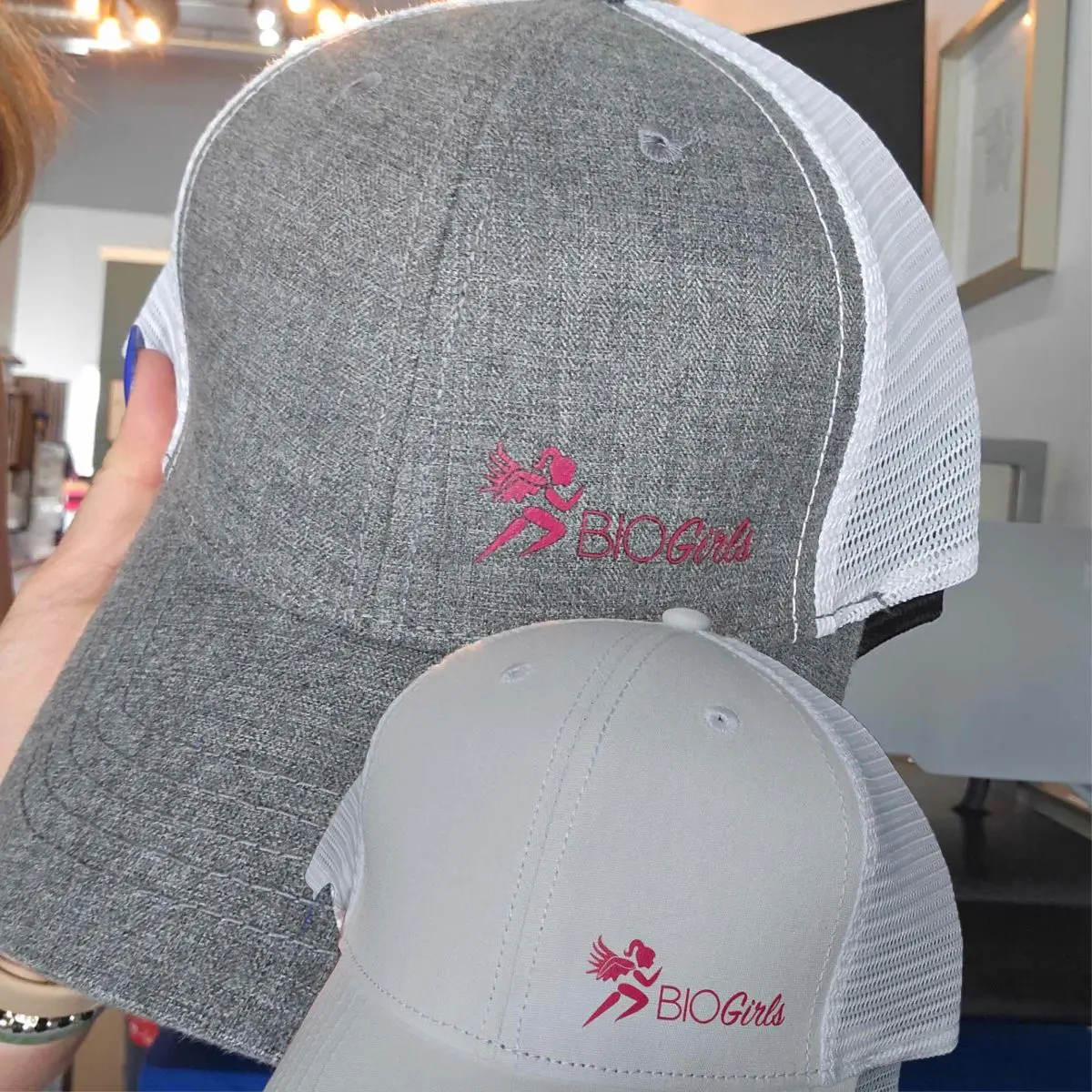 Two hats with a person holding them up.