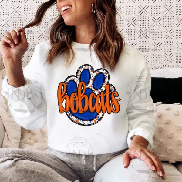 A woman sitting on the couch wearing a white sweatshirt.