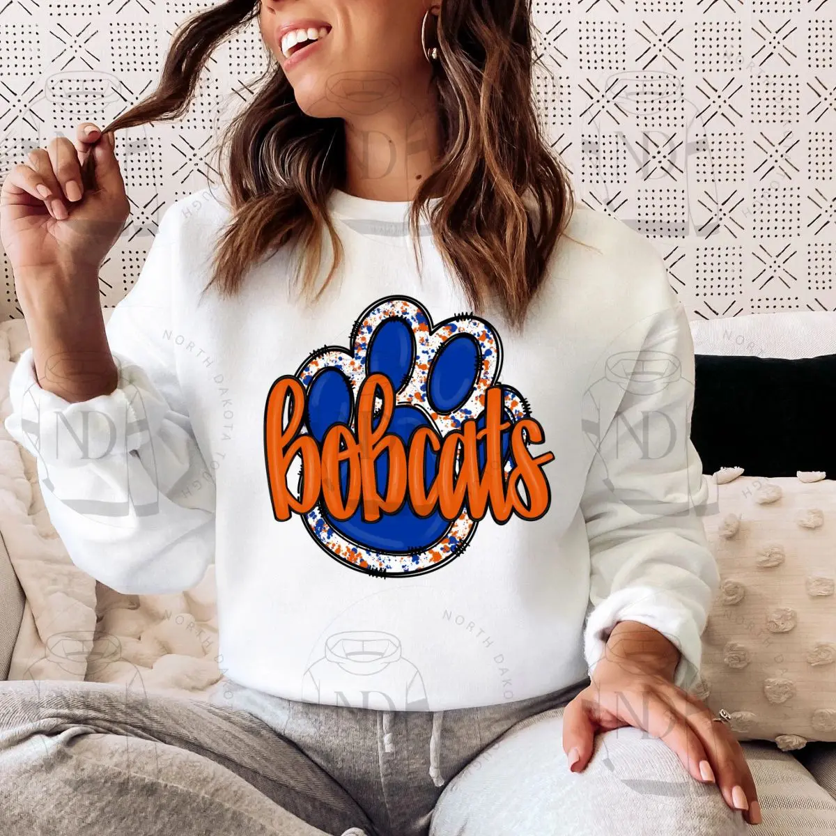 A woman sitting on the couch wearing a white sweatshirt.