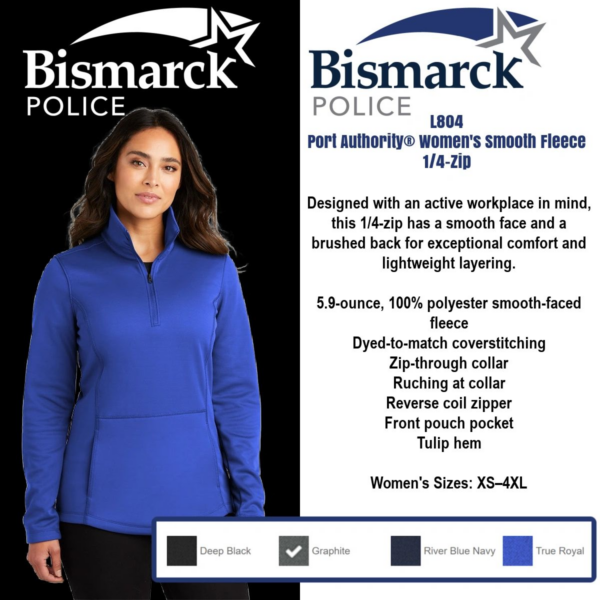 A woman wearing a blue jacket and standing next to a white wall.