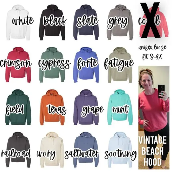 A woman holding her phone in front of a bunch of different colored hoodies.