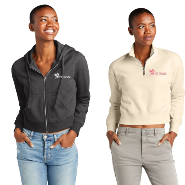 Two women wearing jackets and jeans are smiling.