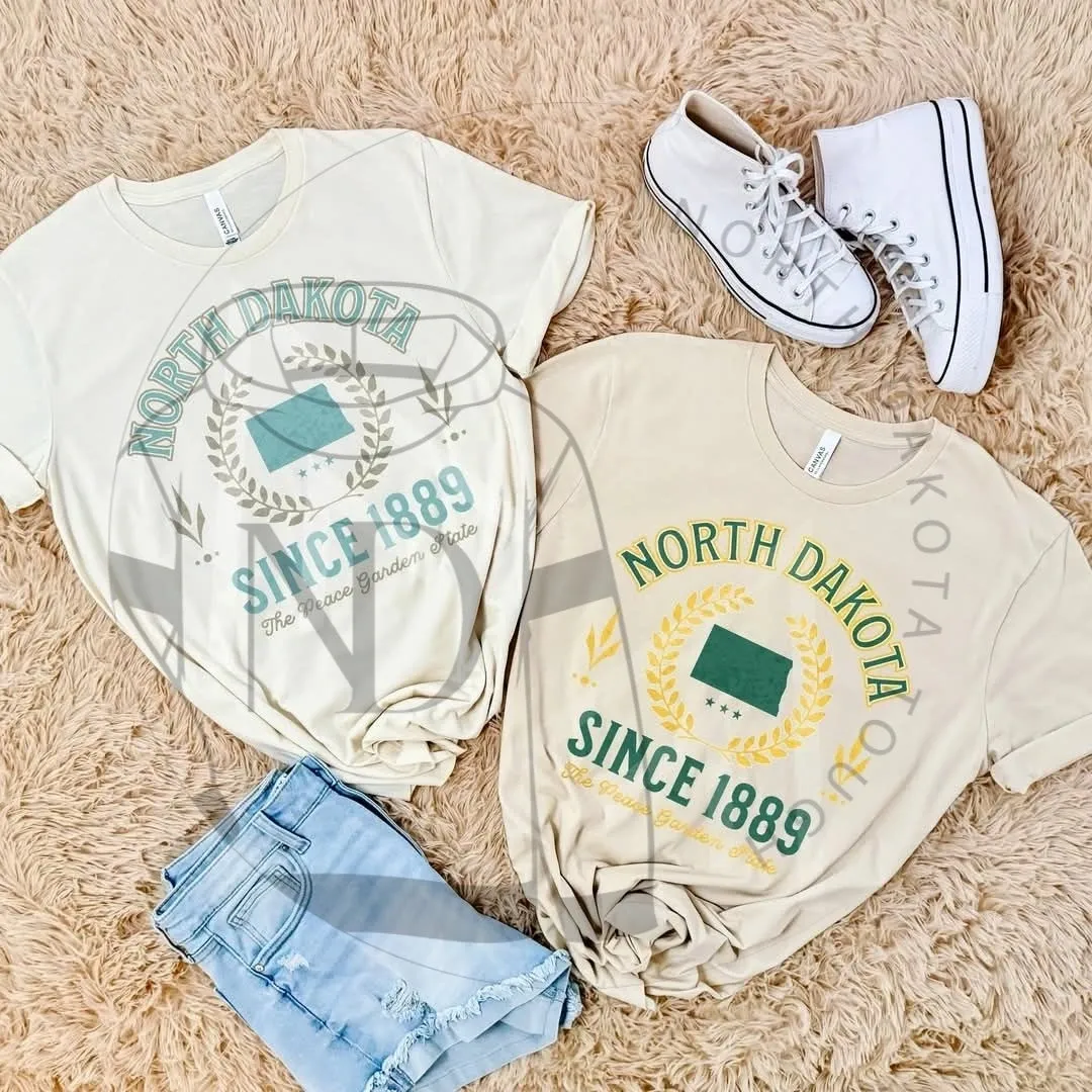 A pair of white shoes and two t-shirts on the floor.